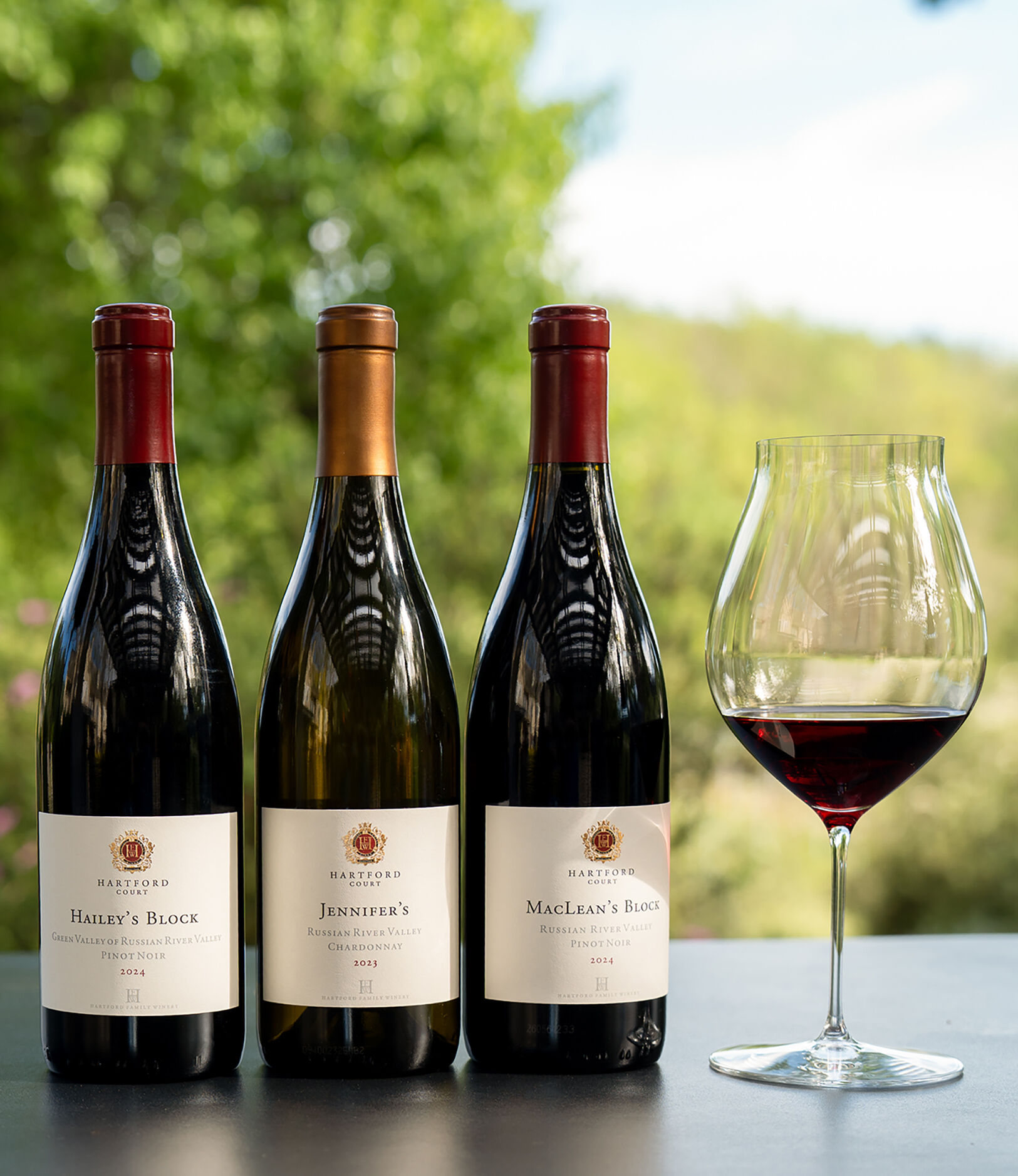 3 bottles of Hartford wines outside with a poured glass of Pinot Noir